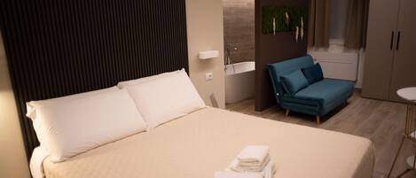 Una habitación de hotel con cama, sofá, una mesita y zona de ducha.