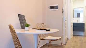 A small dining area with a round table, two chairs, a potted plant, and a remote control.