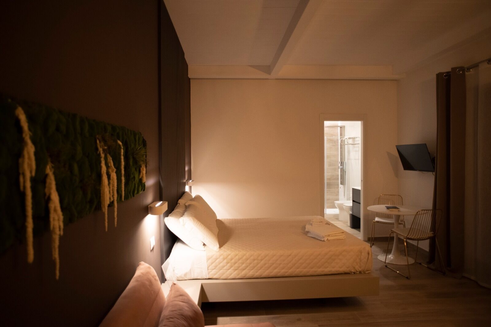 A modern bedroom with a bed, bedside table, and a TV mounted on the wall.
