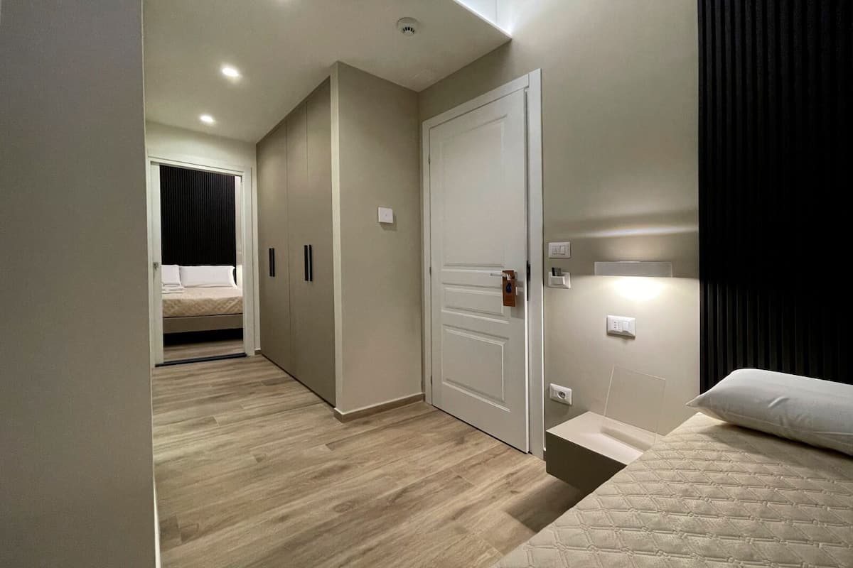 A bedroom with a bed, a wardrobe, a door, and a bedside table.