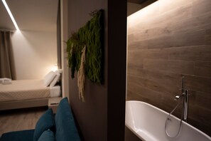 Ein modernes Hotelzimmer mit einem Bett, einer Wandpflanze und einer Badewanne.
