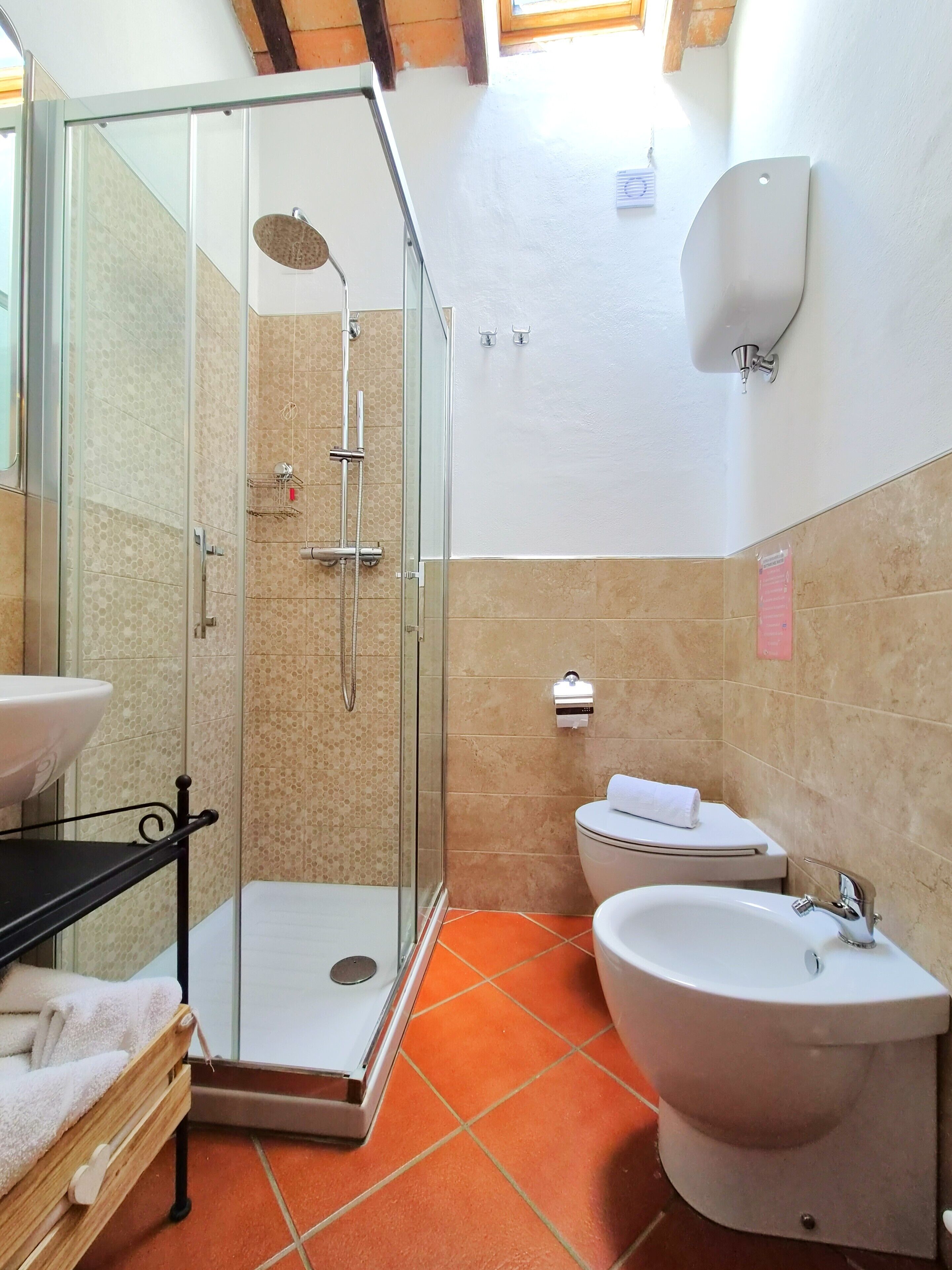 A bathroom with a glass-enclosed shower, a toilet, a sink, and a towel rack.