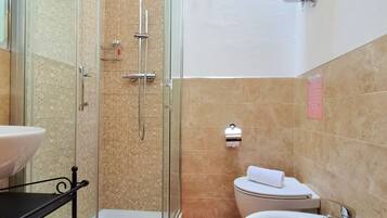 A bathroom with a glass-enclosed shower, a toilet, a sink, and a towel rack.