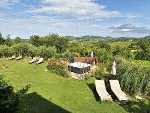 A garden with lounge chairs, a hot tub, and a view of the countryside. - B&B Il Casale di Sandra (Chiusi)