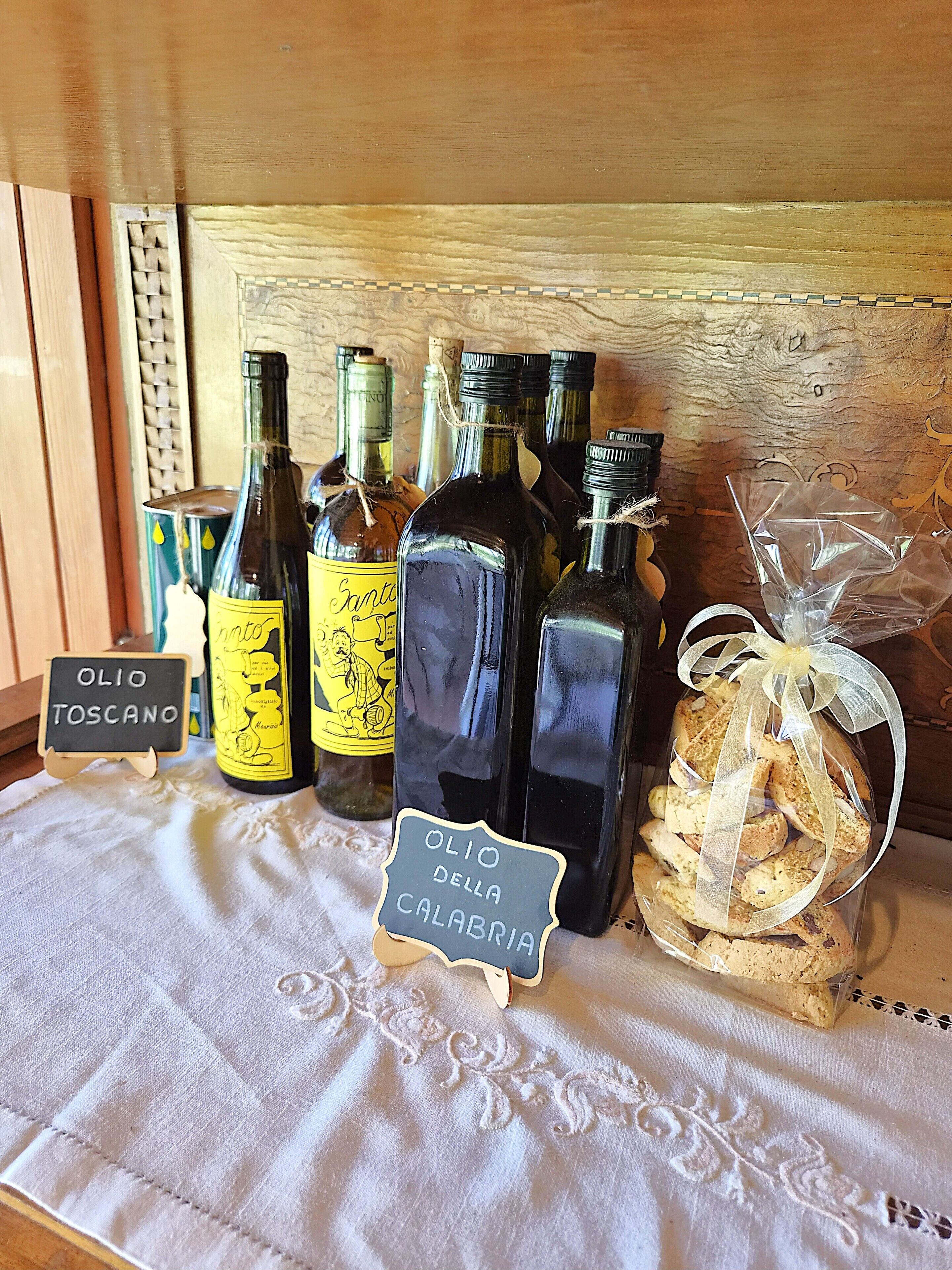 A display of olive oil bottles and cookies on a table with a chalkboard sign.