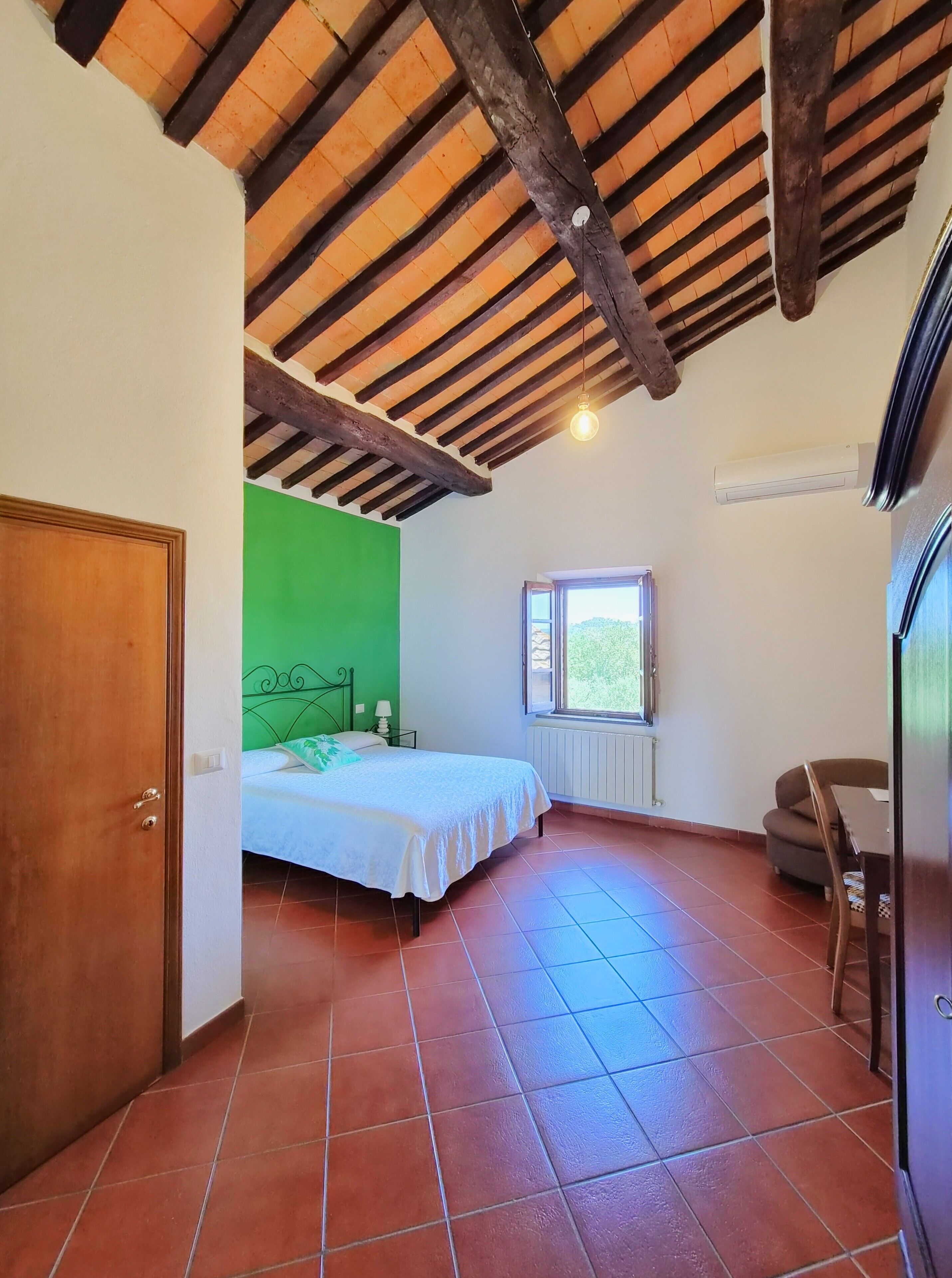 A bedroom with a bed, a window, a radiator, and a door.