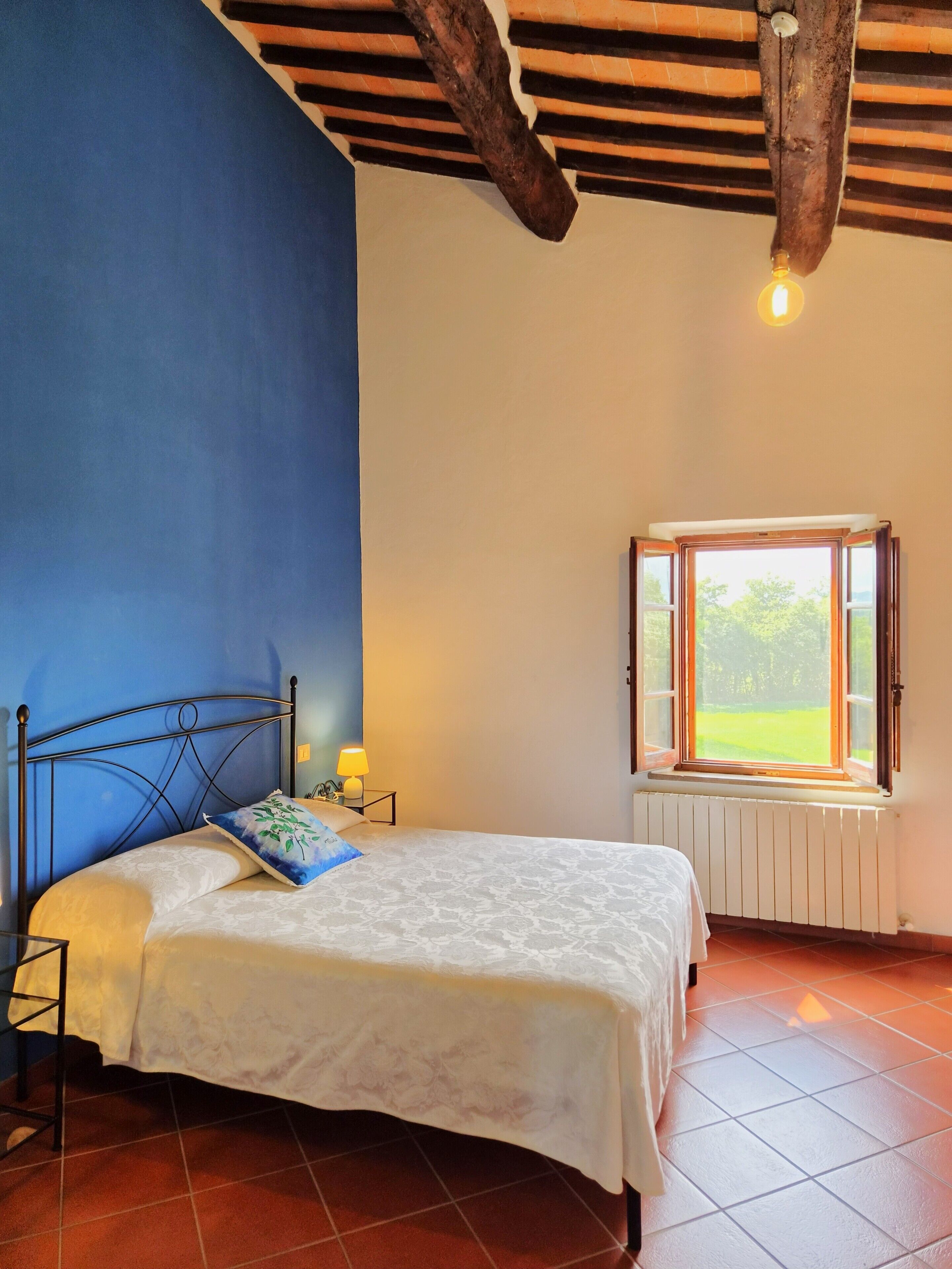 Une chambre à coucher avec un lit, une table de chevet, une fenêtre et un radiateur.