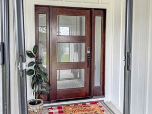 Eine Holztür mit Glasfeldern, ein Blumentopf und eine Fußmatte.