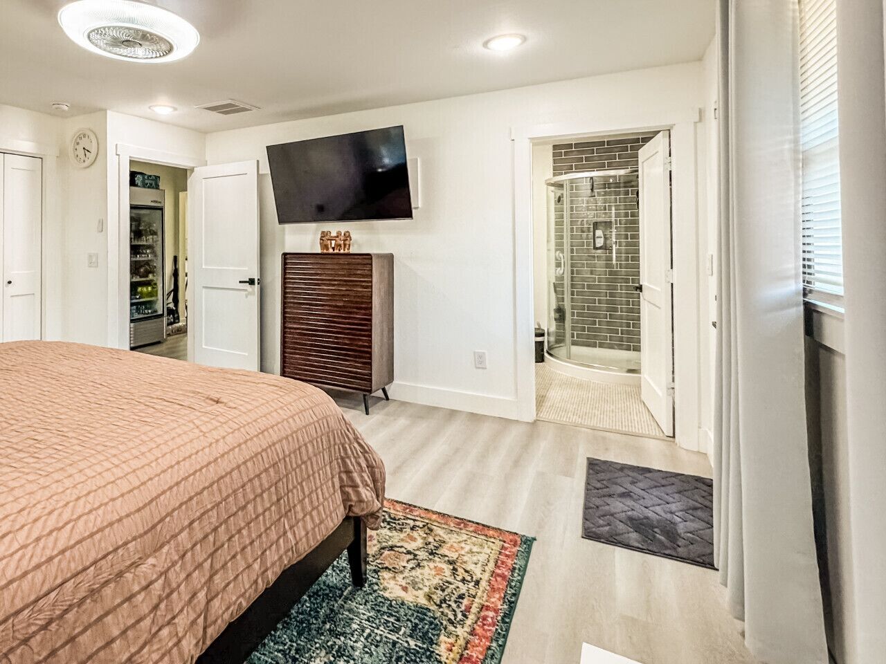 Ein Schlafzimmer mit Bett, Fernseher, Kleiderschrank und einem Badezimmer mit Dusche und Toilette.
