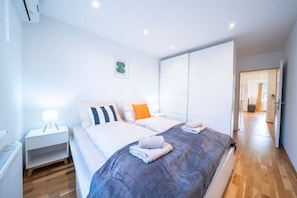 Ein modernes Schlafzimmer mit einem großen Bett, Nachttischen und Blick in einen anderen Raum.