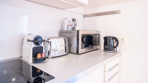 Ett modernt kök med en brödrost, mikrovågsugn och kaffebryggare på bänkskivan.