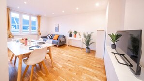 Ett modernt vardagsrum med en matplats, en soffa, en tv och en krukväxt.