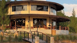 A multi-level building with a thatched roof, large windows, and outdoor seating areas.