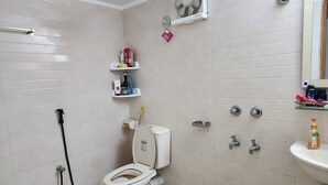 Un baño con inodoro, ducha, lavabo y espejo.