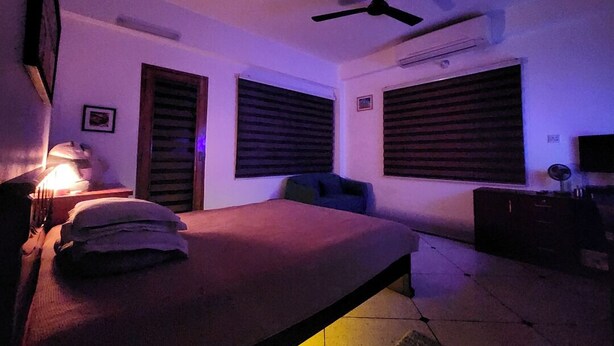 Un dormitorio con una cama, un ventilador de techo y dos ventanas con persianas.