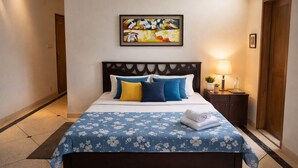 Una habitación de hotel con una cama, una mesita de noche, un cuadro enmarcado y una puerta.
