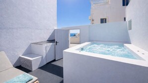 Una terraza en la azotea con jacuzzi, zona de estar y vistas al mar.
