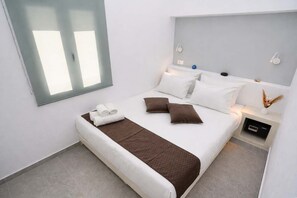 Une chambre d’hôtel moderne avec un grand lit, une table de chevet avec une lampe et un luminaire fixé au mur.