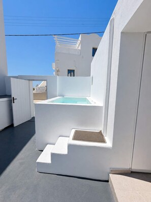 A white building with a pool, steps leading to a door, and a clear blue sky.