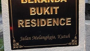 Ein Schild für 'Beranda Bukit Residence' mit einer goldfarbenen Beschilderung an einer strukturierten Wand.