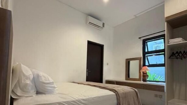 Ein Schlafzimmer mit Bett, Fenster mit Aussicht, Tür und Klimaanlage.