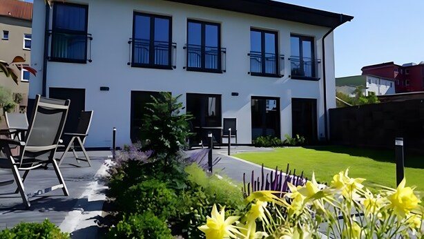 A modern two-story building with large windows, outdoor seating, and a well-maintained garden. - Central Suite ll – Cozy Holiday Home in Greifswald for 2 Guests (Greifswald)