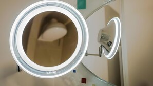A bathroom with a round mirror, a toilet, and a sink. - Central Suite ll – Cozy Holiday Home in Greifswald for 2 Guests (Greifswald)