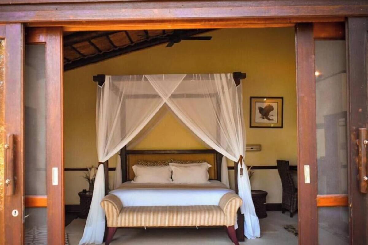 A room with a bed, a bench, and a canopy.