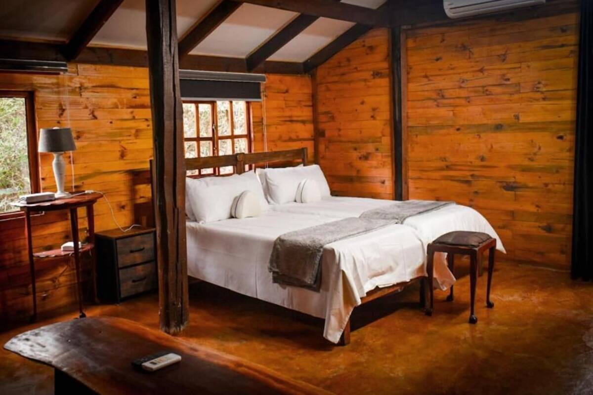 A wooden cabin bedroom with a bed, bedside tables, and a window.