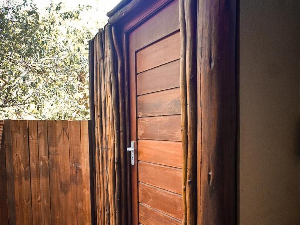 A wooden door with a metal handle, a wooden fence, and a tree in the background.