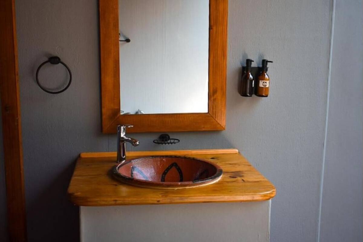 A bathroom with a wooden vanity, a round sink, a mirror, and a towel ring.