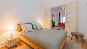 Ein Schlafzimmer mit Bett, Nachttischlampe und einem kleinen Hocker.