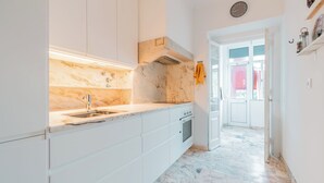 Eine moderne Küche mit weißen Schränken, einer Marmorarbeitsplatte und einem eingebauten Backofen.