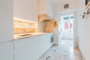 A modern kitchen with white cabinetry, a marble countertop, and a built-in oven. - Spacious T3 in Avenida de Berna | Central | Ideal for families (Lisboa)