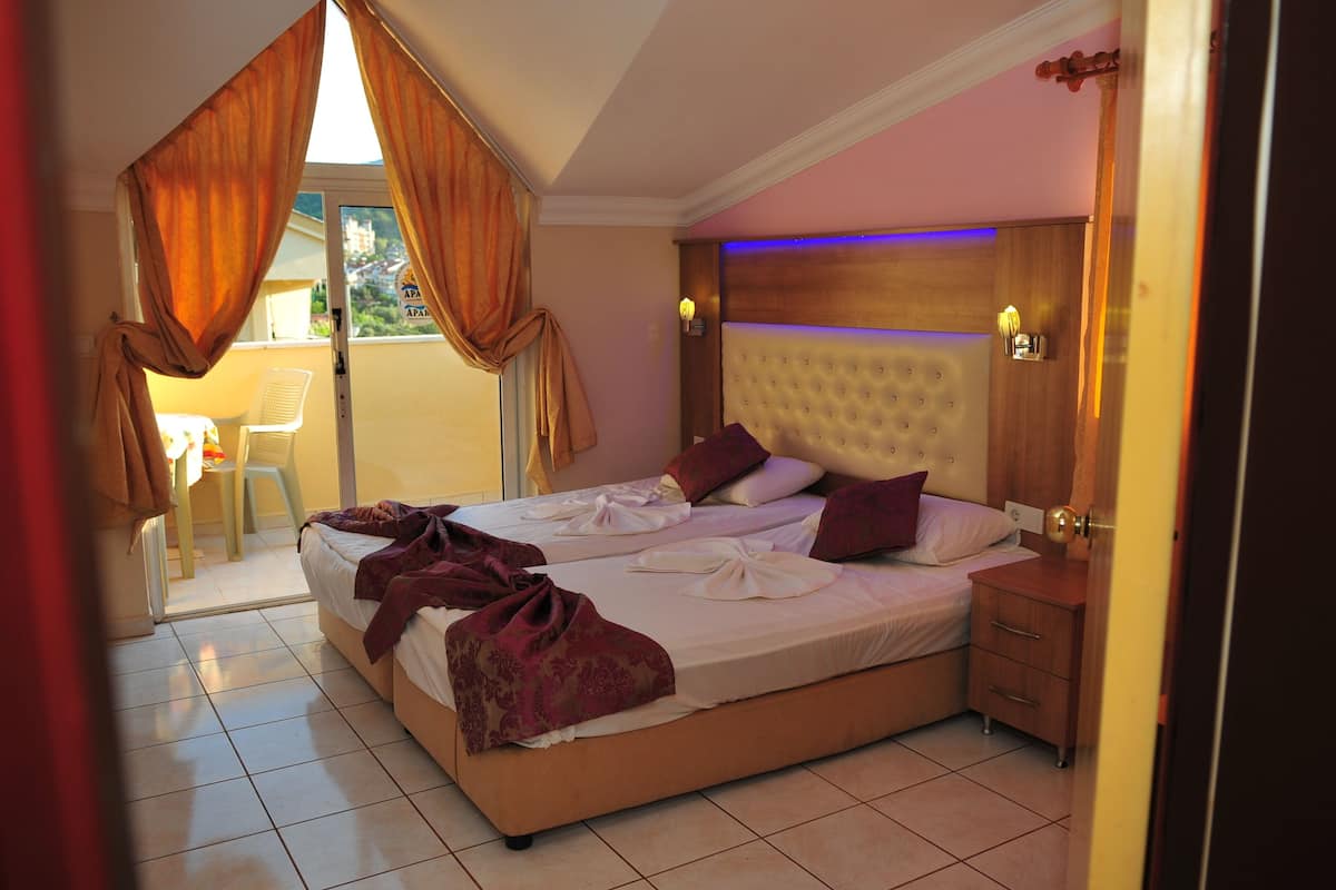 Ein Hotelzimmer mit einem großen Bett, einem Holzkopfstück, einem kleinen Nachttisch und Blick ins Freie.