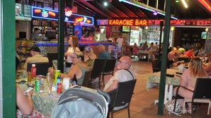 A bar with neon signs, tables, and chairs for patrons.