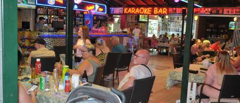 A bar with neon signs, tables, and chairs for patrons.