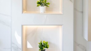 Een muur met drie verlichte planken, elk voorzien van een potplant.