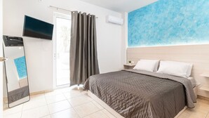 Een moderne slaapkamer met een bed, een televisie, een raam met gordijnen en een blauwe muur.