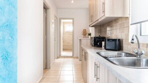Een moderne keuken met een RVS spoelbak, houten kastjes en een aanrecht met een koffieapparaat.