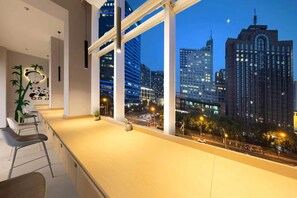 A modern room with a large window overlooking a cityscape at dusk. - hocoshulvjiudian (Beijing)