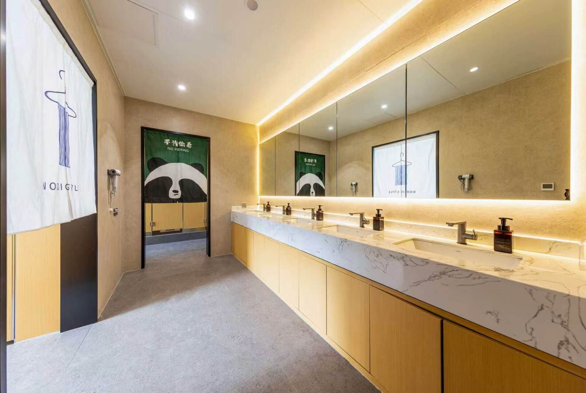 Ein modernes Badezimmer mit einem langen Waschtisch, mehreren Waschbecken und einem großen Spiegel.