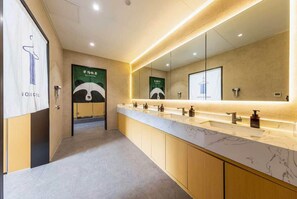 Une salle de bain moderne avec un long meuble-lavabo, plusieurs vasques et un grand miroir.