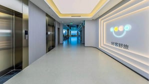 Un pasillo moderno de hotel con ascensores, una zona de recepción y una pared con el logotipo de una cara sonriente.