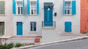A building with white walls, blue shutters, and a balcony with a metal railing.