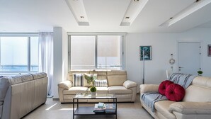 A modern living room with two sofas, a coffee table, and a view of the sea. - Panoramic 2-BR Apt & Balcony in Larnca (Larnaca)