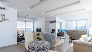 A modern living room with a sofa, armchairs, a coffee table, and a television. - Panoramic 2-BR Apt & Balcony in Larnca (Larnaca)