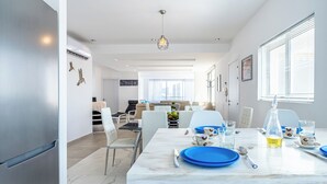 A modern kitchen with a marble countertop, dining area with chairs, and a view of the cityscape. - Panoramic 2-BR Apt & Balcony in Larnca (Larnaca)