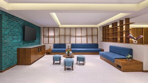 Uma sala de estar moderna com um sofá azul, uma televisão de tela plana presa em uma parede de tijolos e uma estante de madeira.