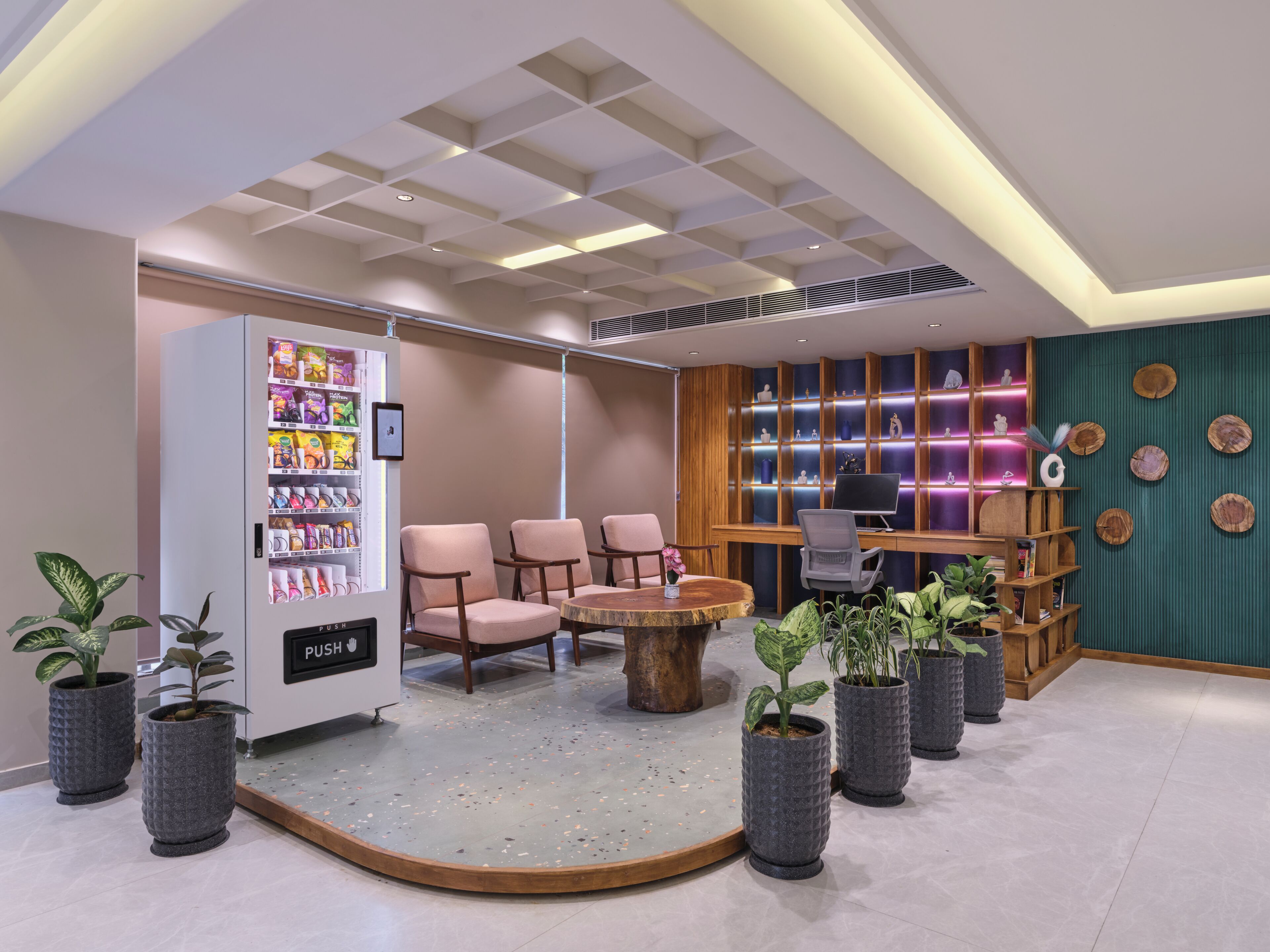 Een moderne lobby met een automaat, een zithoek en een bureau met een computer.